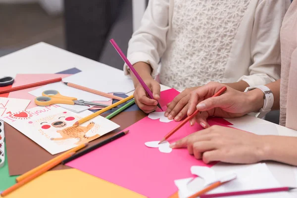 Imagen recortada de la madre y la hija afroamericanas haciendo corazones de papel para la tarjeta de felicitación - foto de stock