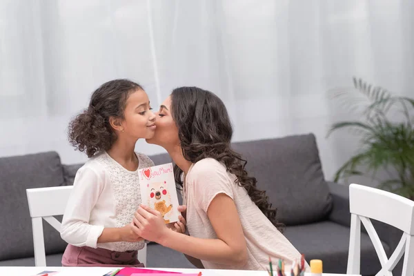 African american mother kissing daughter for greeting card on mothers day — Stock Photo