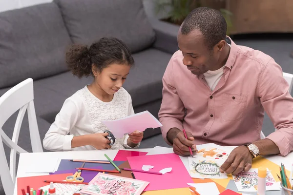 Африканская американская дочь режет бумагу для поздравительной открытки на день матери — стоковое фото