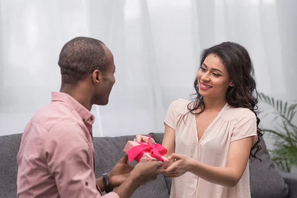 Fidanzato afro-americano che presenta regalo alla fidanzata nel giorno internazionale delle donne — Foto stock