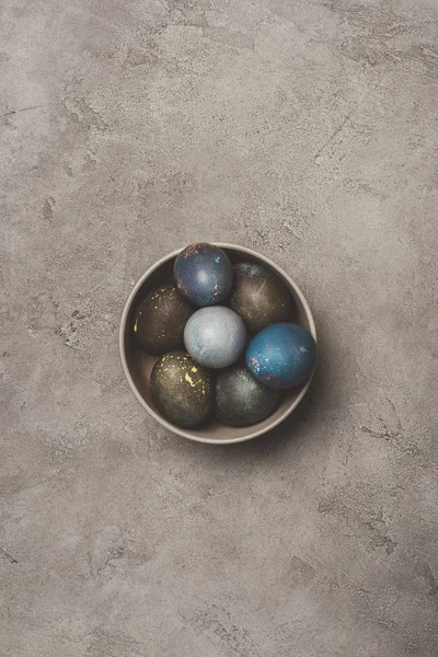 Верхний вид пасхальных яиц в миске на бетонной поверхности — стоковое фото