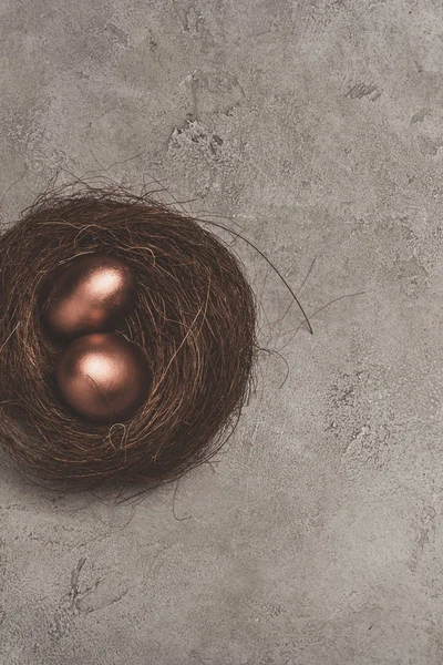 Top view of golden easter eggs in nest on concrete surface — Stock Photo