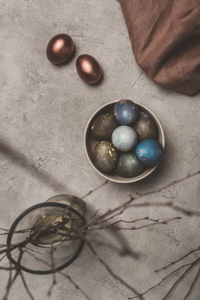 Vue de dessus des œufs de Pâques et des branches de saule en vase sur la surface du béton — Photo de stock