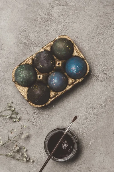 Ansicht von bemalten Ostereiern in goldenem Tablett mit Farbe und Pinsel auf Beton — Stockfoto