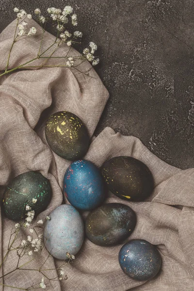Vista dall'alto di uova di Pasqua dipinte male e fiori sulla tovaglia — Foto stock