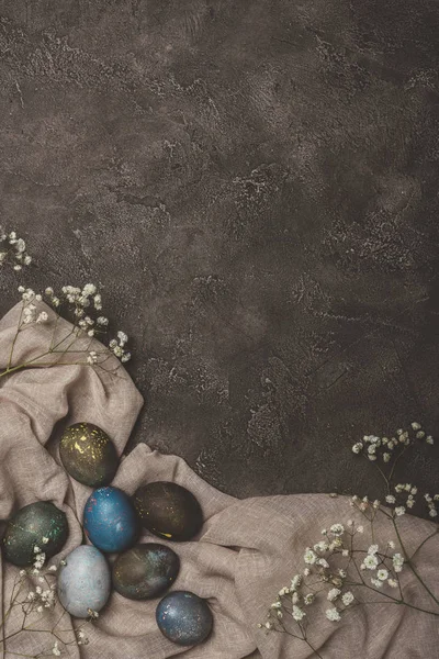 Ansicht von Ostereiern und Blumen auf Tischdecke auf Betonoberfläche — Stockfoto