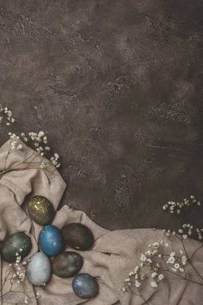 Top view of easter eggs and flowers on tablecloth on concrete surface — Stock Photo