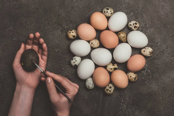 Vista cortada do homem pintando ovo de Páscoa, codorna crua e ovos de galinha perto — Fotografia de Stock