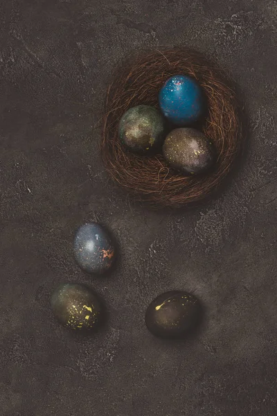 Top view of painted easter eggs in nest on concrete table — Stock Photo