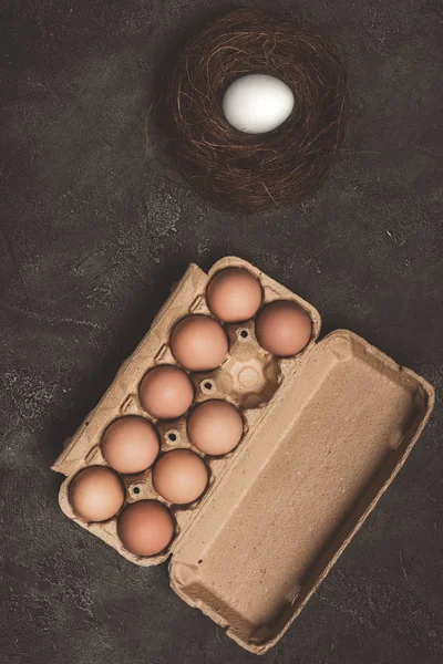 Vista superior de huevos de pollo en bandeja de cartón y nido - foto de stock