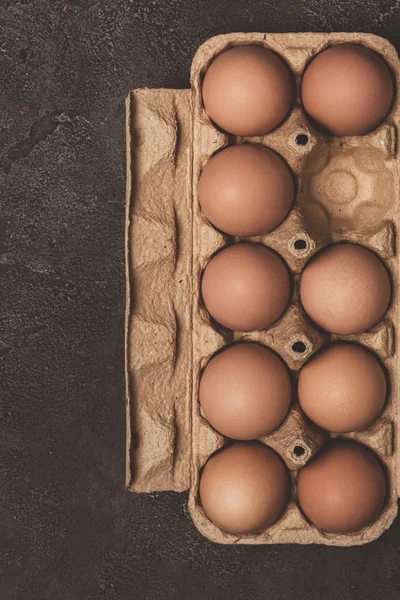 Vue du dessus des œufs de poulet dans un plateau en carton sur fond gris — Photo de stock