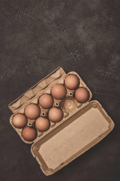 Top view of chicken eggs in cardboard tray on grey concrete — Stock Photo