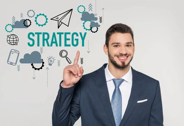 Smiling young businessman pointing up with finger and looking at camera, strategy concept — Stock Photo