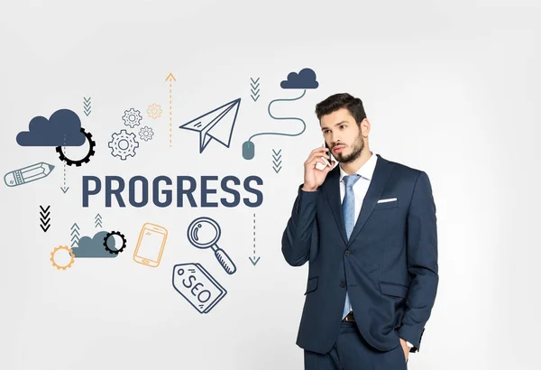 Stylish young businessman standing with hand in pocket and talking on smartphone while looking away isolated on grey, progress icons — Stock Photo