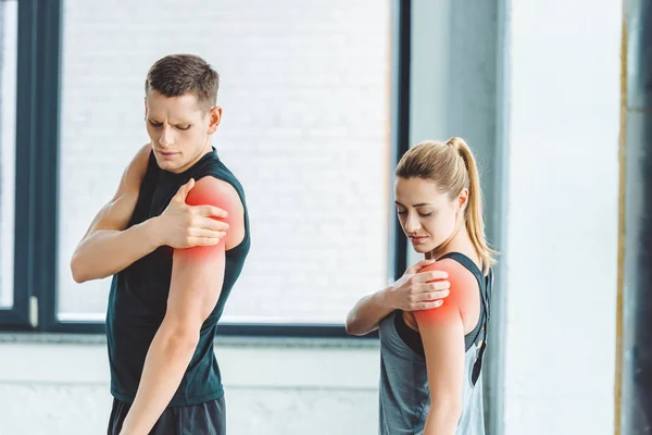 Junges Paar hat Schmerzen in den Armen nach dem Training im Fitnessstudio — Stockfoto