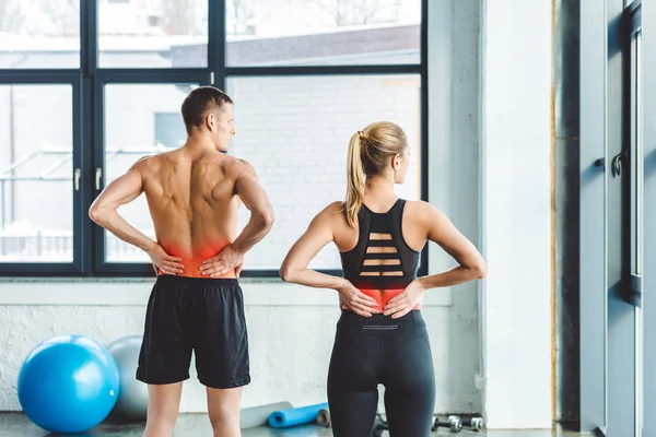 Back view of couple having backache after workout in gym — Stock Photo