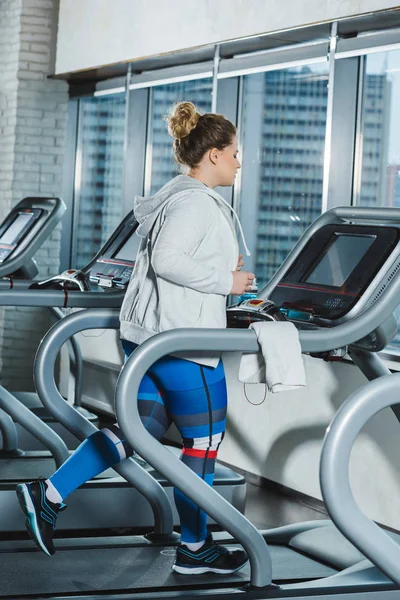 Entrenamiento de mujer con sobrepeso en la cinta de correr en el gimnasio - foto de stock