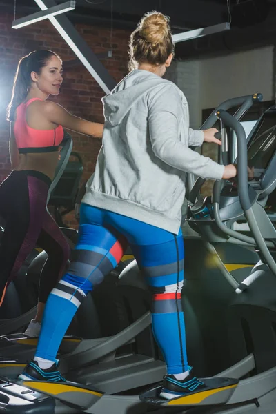 Entrenamiento de las mujeres en la cinta de correr en el gimnasio y mirándose entre sí - foto de stock