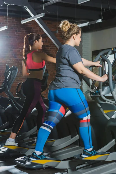 Sportliche und übergewichtige Frauen trainieren im Fitnessstudio auf Laufbändern — Stockfoto