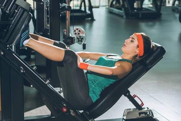 Mujer deportiva piernas de entrenamiento en el aparato de entrenamiento en el gimnasio - foto de stock
