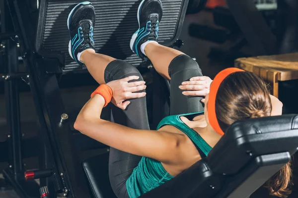 Sporty woman training legs on training apparatus at gym — Stock Photo