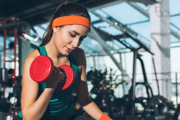 Sporty woman working out with dumbbell at gym — Stock Photo
