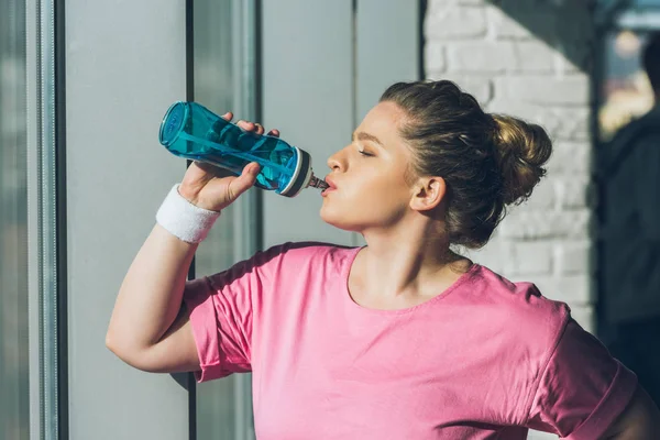 Mujer con sobrepeso beber agua en el gimnasio - foto de stock