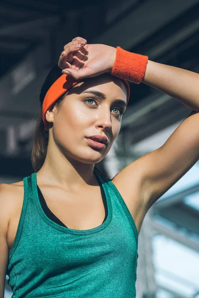 Tired sporty woman with hand on forehead at gym — Stock Photo