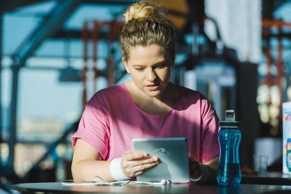 Надмірна вага жінки за допомогою цифрового планшета, сидячи за столом — стокове фото