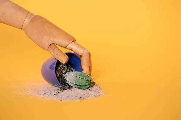 Mano de maniquí y cactus en maceta azul sobre amarillo - foto de stock