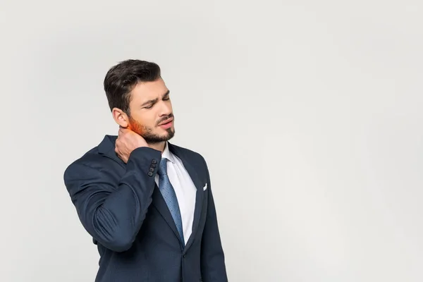 Joven hombre de negocios con los ojos cerrados que sufren de dolor en el cuello aislado en gris - foto de stock