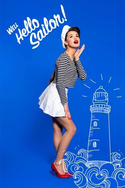 Beautiful young woman in sailor shirt with lighthouse drawing and well hello sailor inscription isolated on blue — Stock Photo