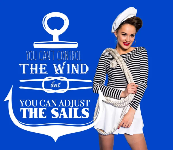 Smiling beautiful young woman in sailor shirt with rope and motivational inscription isolated on blue — Stock Photo