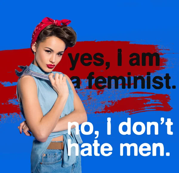 Modische junge Frau in Pin-up-Kleidung mit Schraubenschlüssel und Feminismus Zitat — Stockfoto