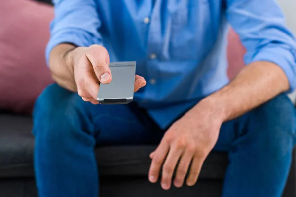 Abgeschnittene Aufnahme eines Mannes, der die Sender wechselt, während er zu Hause fernsieht — Stockfoto