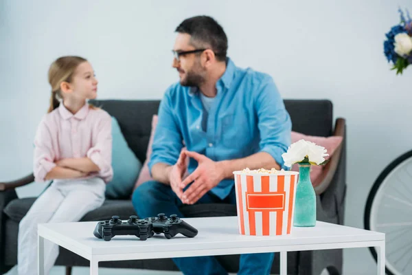 Foco seletivo da família descansando no sofá com gamepads e pipoca na mesa de café — Fotografia de Stock