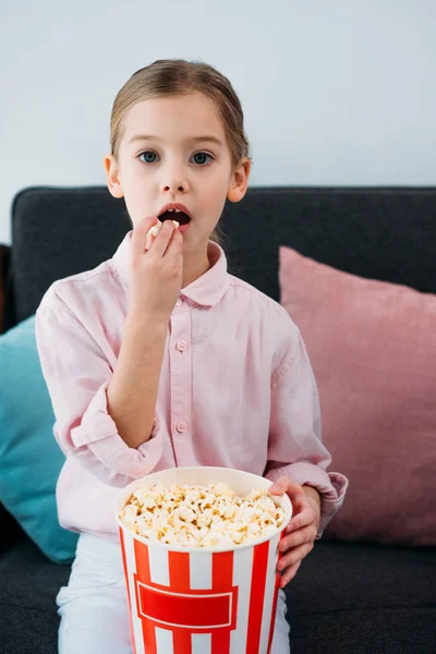 Portrait of kid eating popcorn and watching film at home — Stock Photo