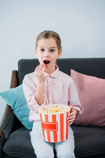 Portrait of kid eating popcorn and watching film at home — Stock Photo