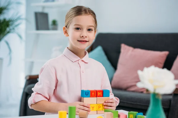 Retrato de niño con bloques de colores en la mesa en la sala de estar en casa - foto de stock