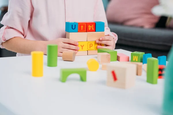 Vista parcial del niño jugando con bloques de colores en casa - foto de stock