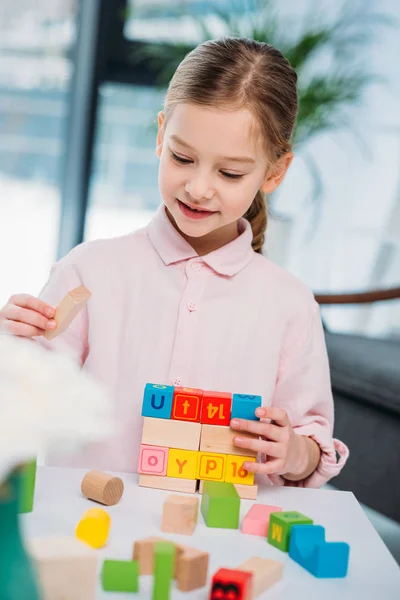 Porträt eines süßen Kindes, das zu Hause mit bunten Blöcken spielt — Stockfoto