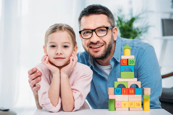 Portrait of family and pyramid from colorful blocks at home — Stock Photo