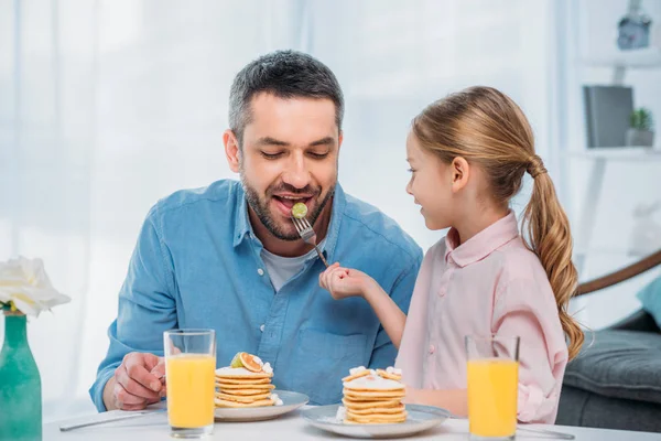 Portrait of father and little daughter having breakfast together at home — Stock Photo