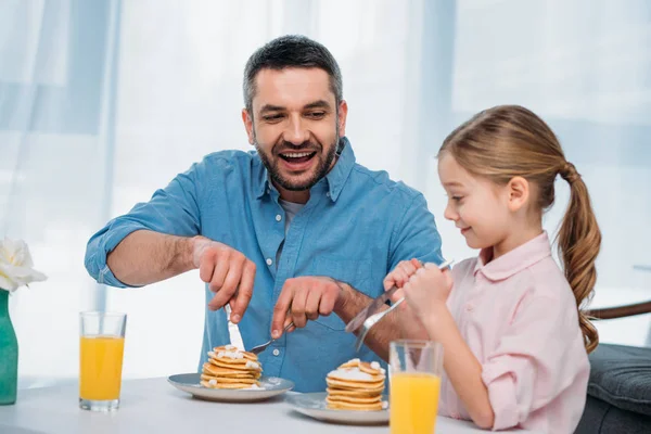Cheerful father and little daughter having breakfast at home — Stock Photo