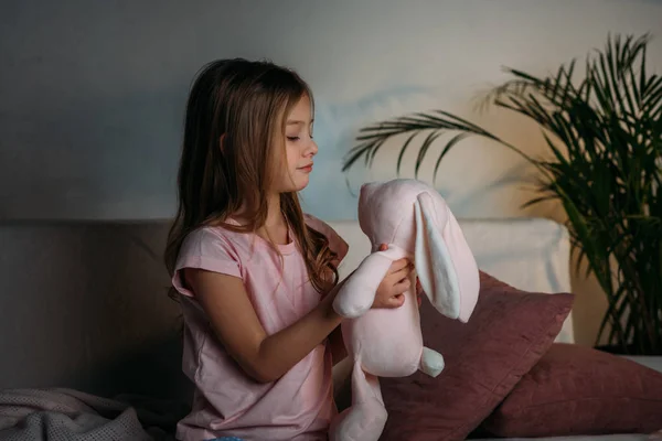 Vista laterale del bambino carino con giocattolo appoggiato sul divano — Foto stock