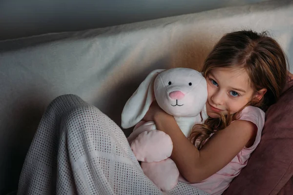 Portrait of cute kid with toy resting on sofa — Stock Photo