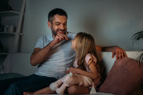 Père jouer avec la petite fille tout en se reposant sur le canapé dans la soirée — Photo de stock