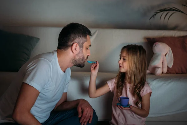 Padre e hija fingiendo tener una fiesta de té juntos en casa - foto de stock