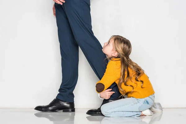 Figlioletta abbracciare padre in abito da lavoro isolato su grigio, concetto di solitudine — Foto stock