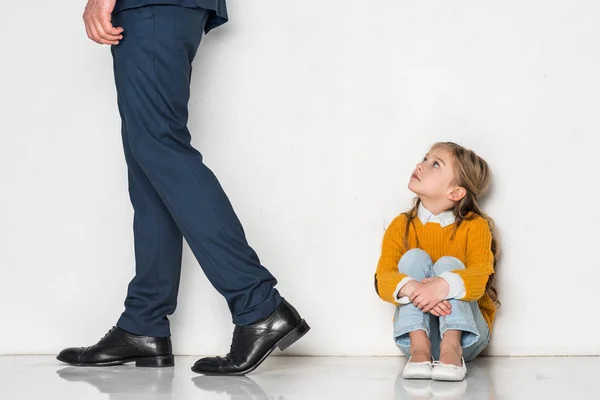 Aufgebrachte Tochter sieht Vater im Geschäftsanzug vereinzelt auf grauem Grund davonlaufen — Stockfoto